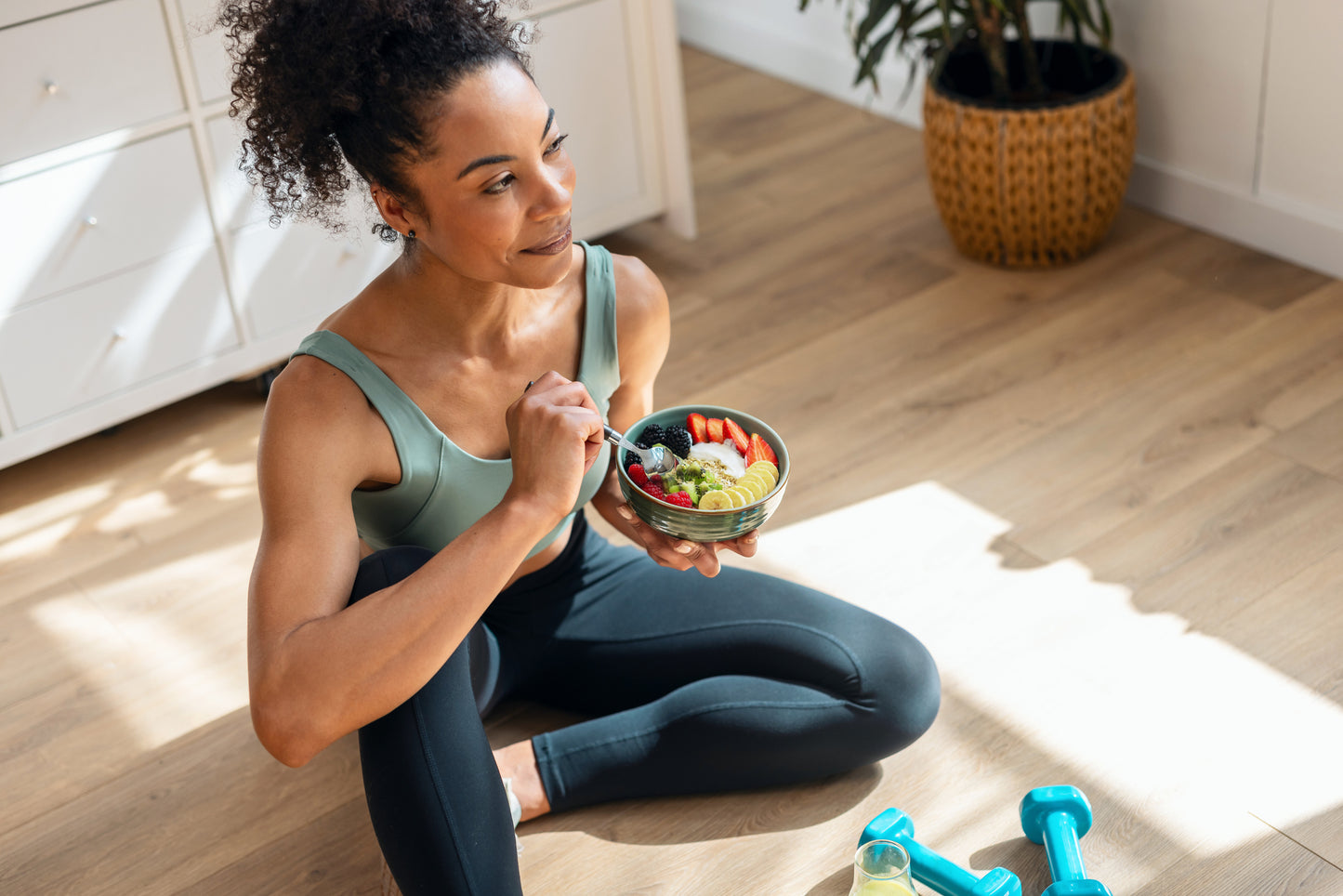 A woman eating a healthy bowl of fruit with weights